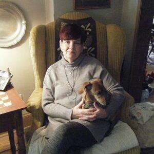 A person sitting in a chair holding a dog

Description automatically generated