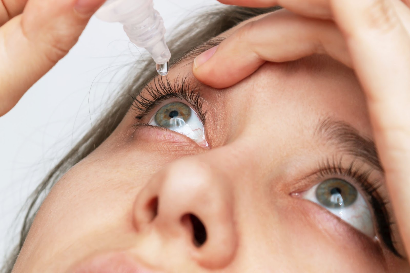 Close up of adult putting medicinal eye drops into their eyes.