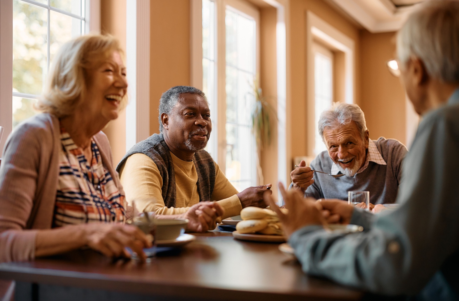 Group of seniors smiling and enjoying a meal together in a social setting.