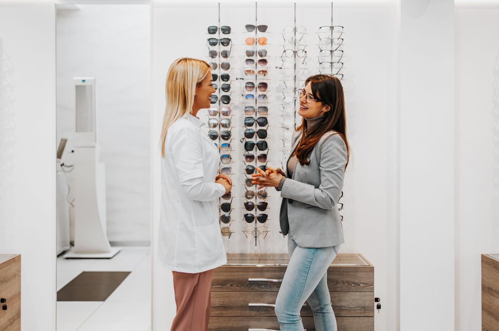 An optician helping a patient choose eyeglass frames to suit their face shape.
