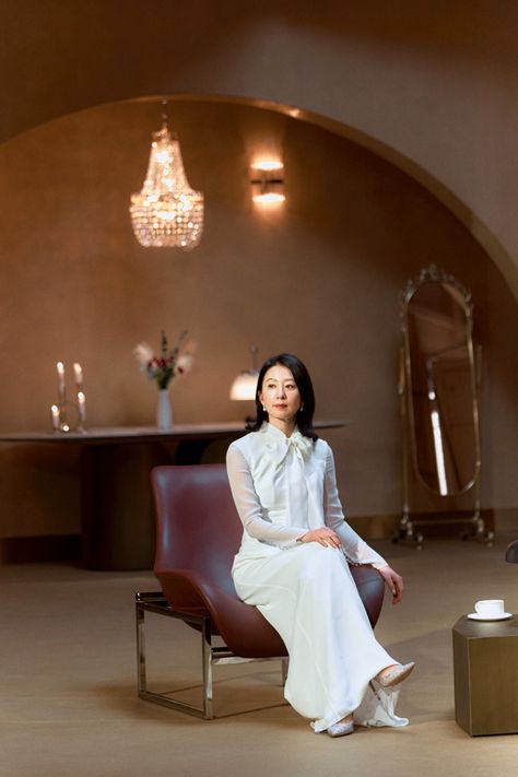 This contains a picture of Kim Hee Ae  sitting on a chair in a room