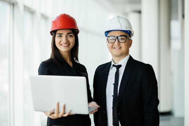 engineering and architecture concept. engineers working on a building site holding a laptop, architect man working with engineer woman inspection in workplace for architectural plan