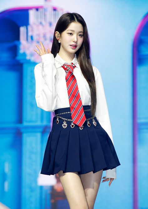 This is a picture of wonyoung wearing a white shirt, red and stripped tie with a black mini skirt