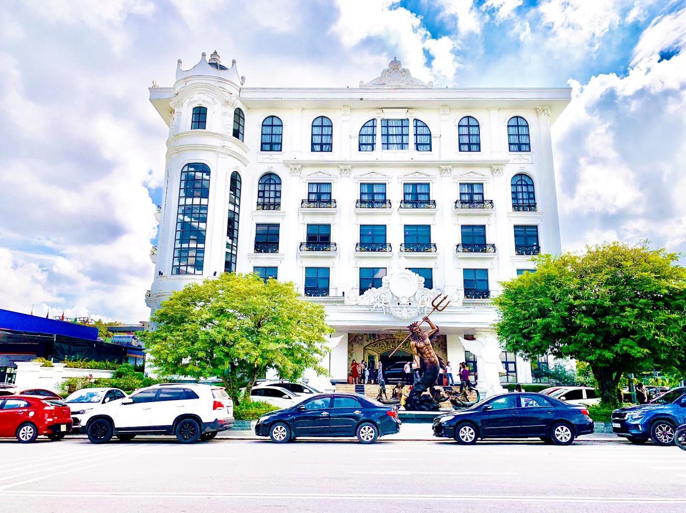 A white building with many windows and cars parked in front of it

Description automatically generated