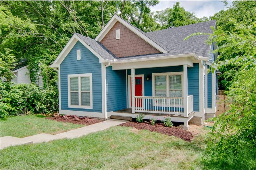 Front exterior view showing the blue horizontal siding, cedar shake accents, and a covered porch with a red entry door.
