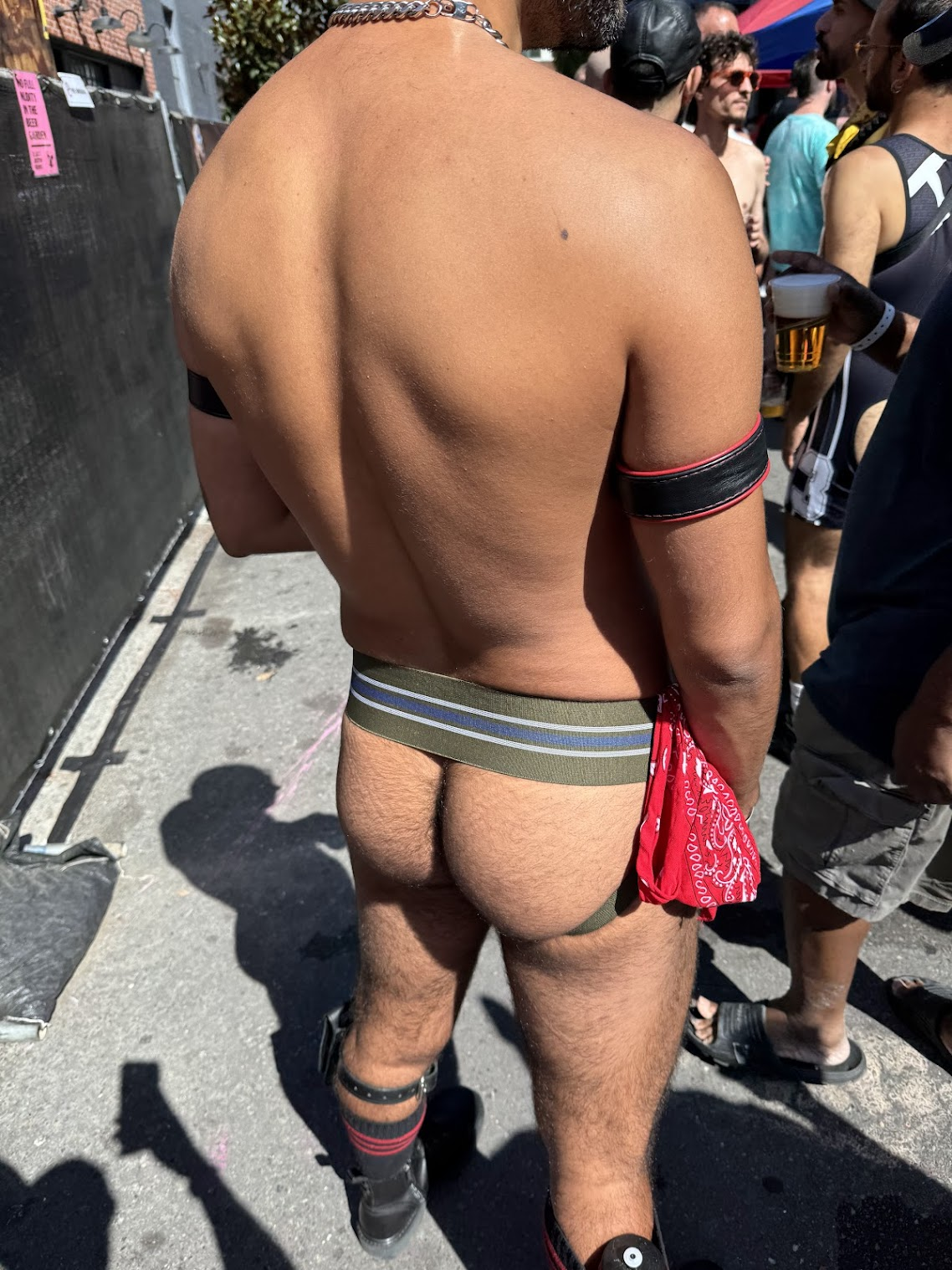 close up of Phil's gay bubble butt in blue and green jockstrap with gay fisting hankerchief standing outside in the streets of Folsom durng Folsom Street fair 2024