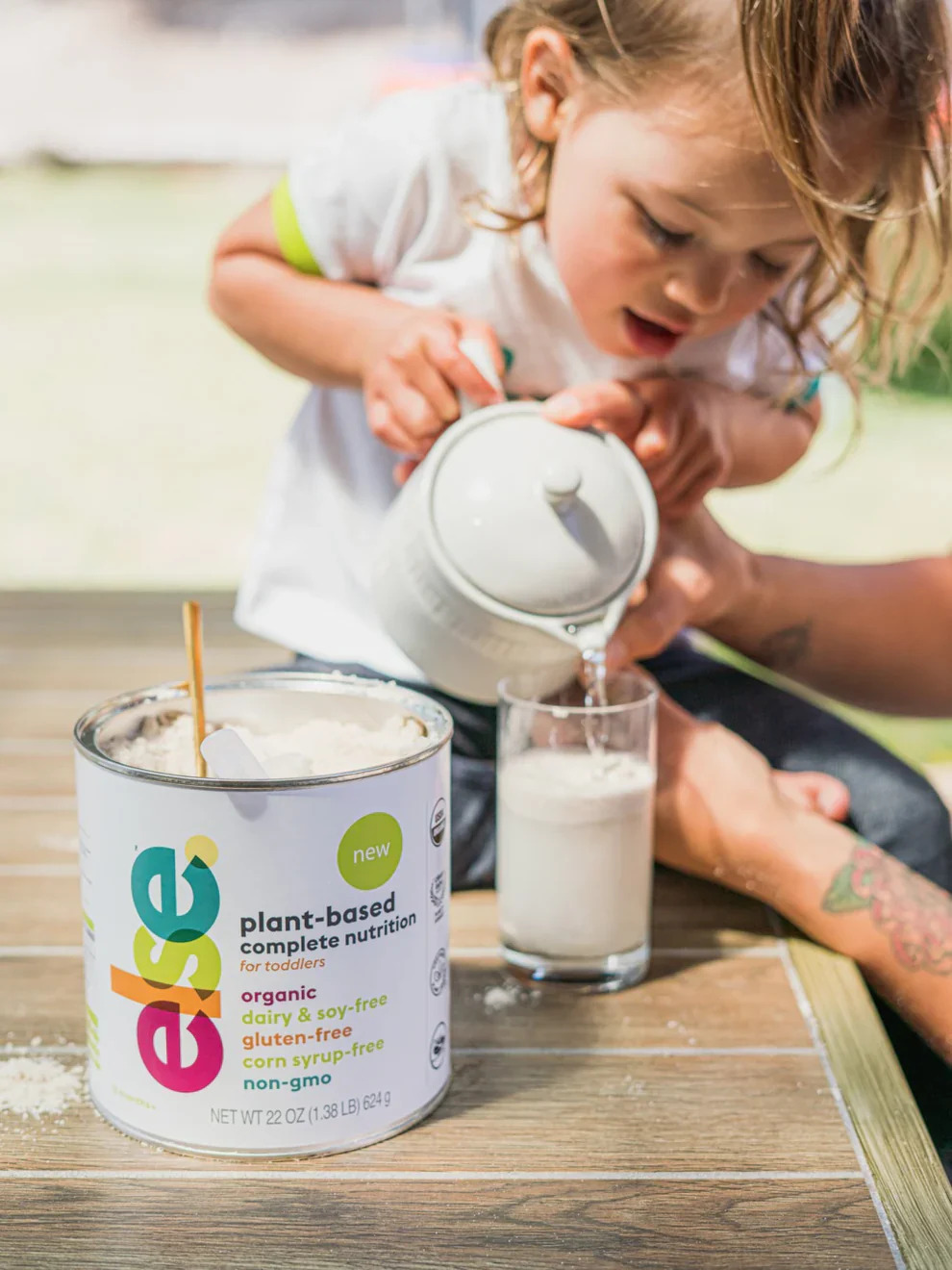 At a table, a woman and a child share a moment together, with a container of milk nearby.