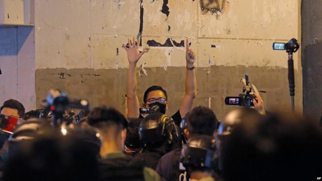 资料照:前香港民主派立法会议员林卓廷(中)在纪念元朗地铁袭击事件一周年的新闻发布会上被防暴警察包围,他用五个手指表达“五项诉求,一个都不能少”的抗议诉求。 (2020年7月21日)