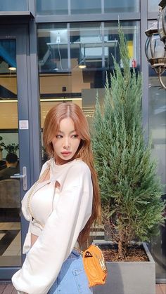 This contain an image of Jessi with a red hair standing in front of a building and posing for the camera