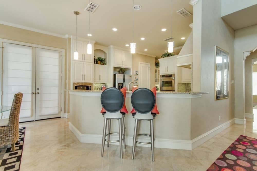 Round bar stools accentuated with orange pillows complement the kitchen peninsula.