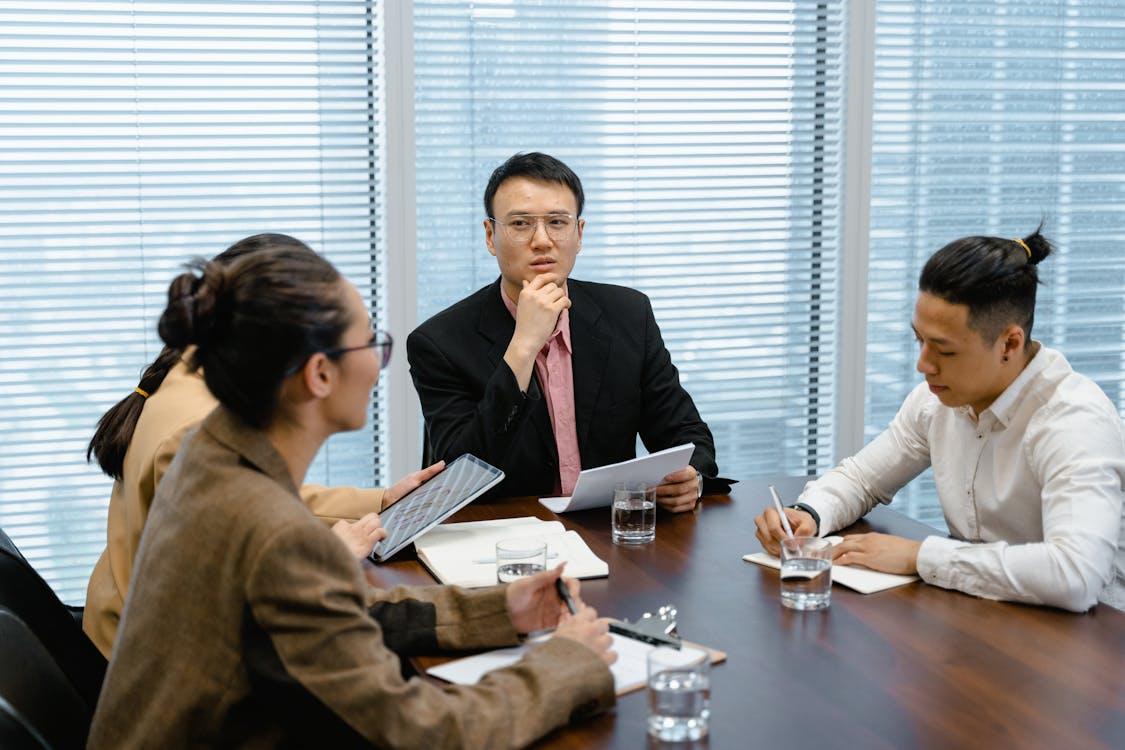 Free Business professionals holding a serious meeting in a modern office environment with technology and documents. Stock Photo