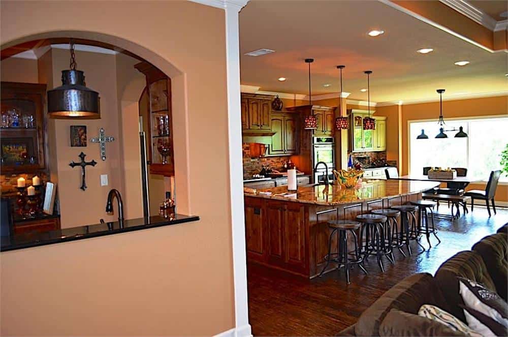 An open layout view showing the family room, kitchen, and breakfast nook. An open arch on the side frames the wet bar.