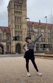 A person posing in front of a building

Description automatically generated with medium confidence