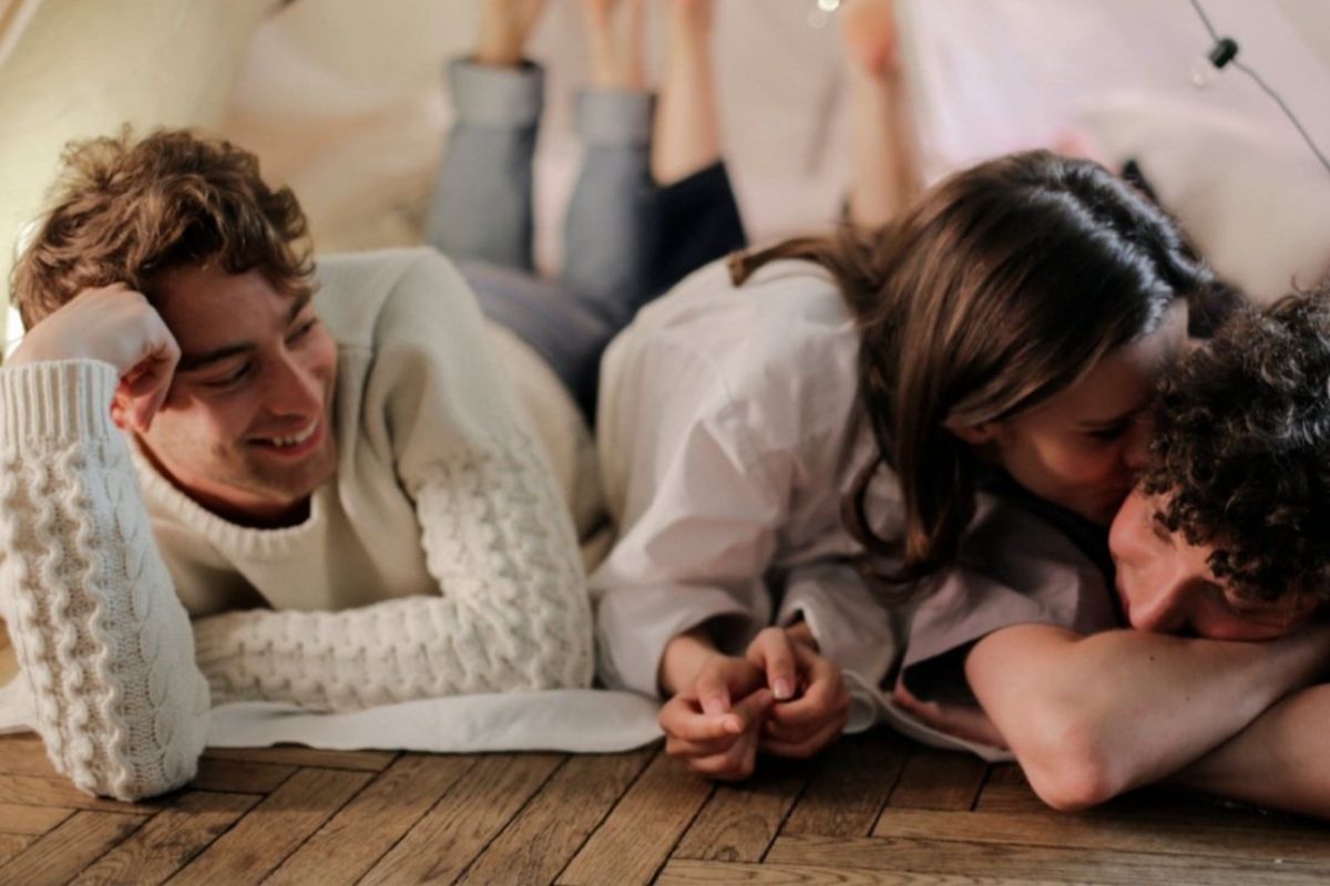 Mulher e dois homens rindo deitados no chão