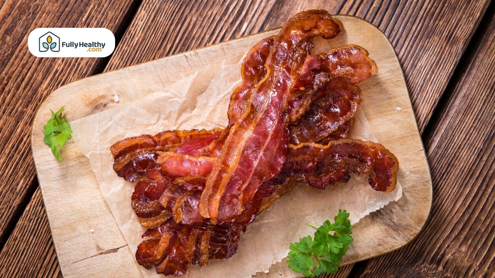 Juicy bacon slices on parchment over wood board with herbs