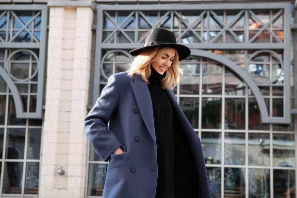 A woman styling a blue long coat with a black hat