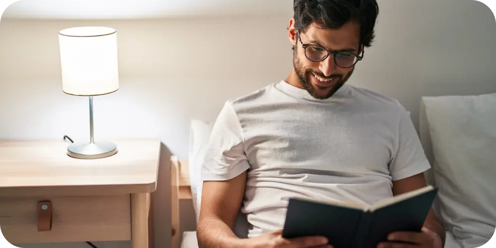 man reading book in bed