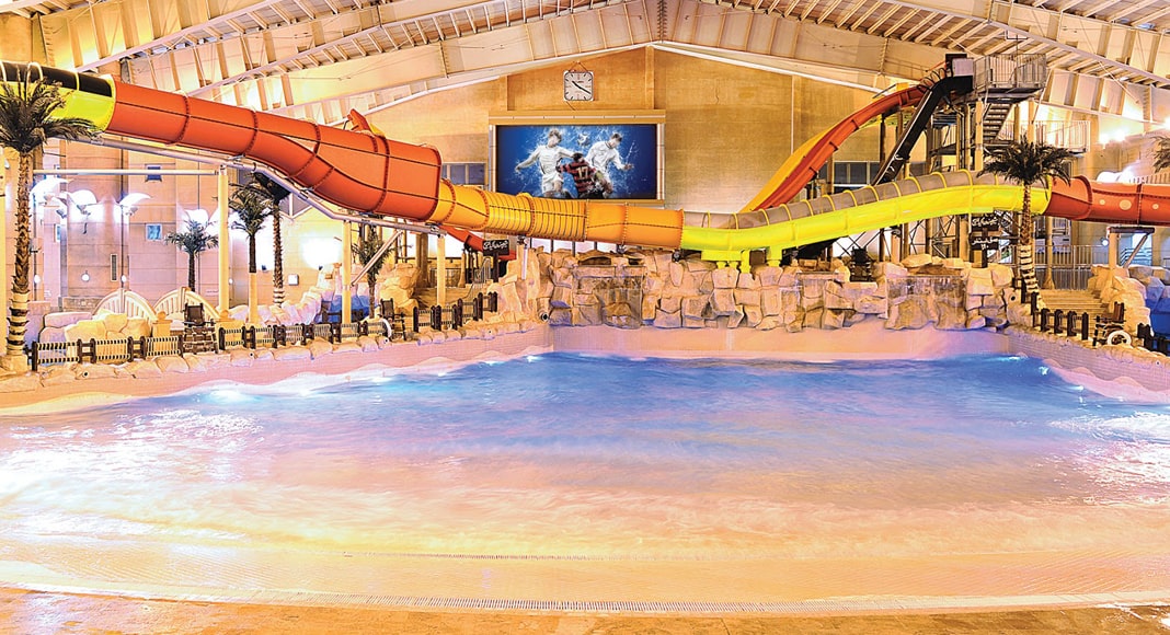 Indoor view of Water Wave Land in Mashhad, featuring colorful water slides, a wave pool, and tropical-themed decor, offering a fun and exciting water park experience.