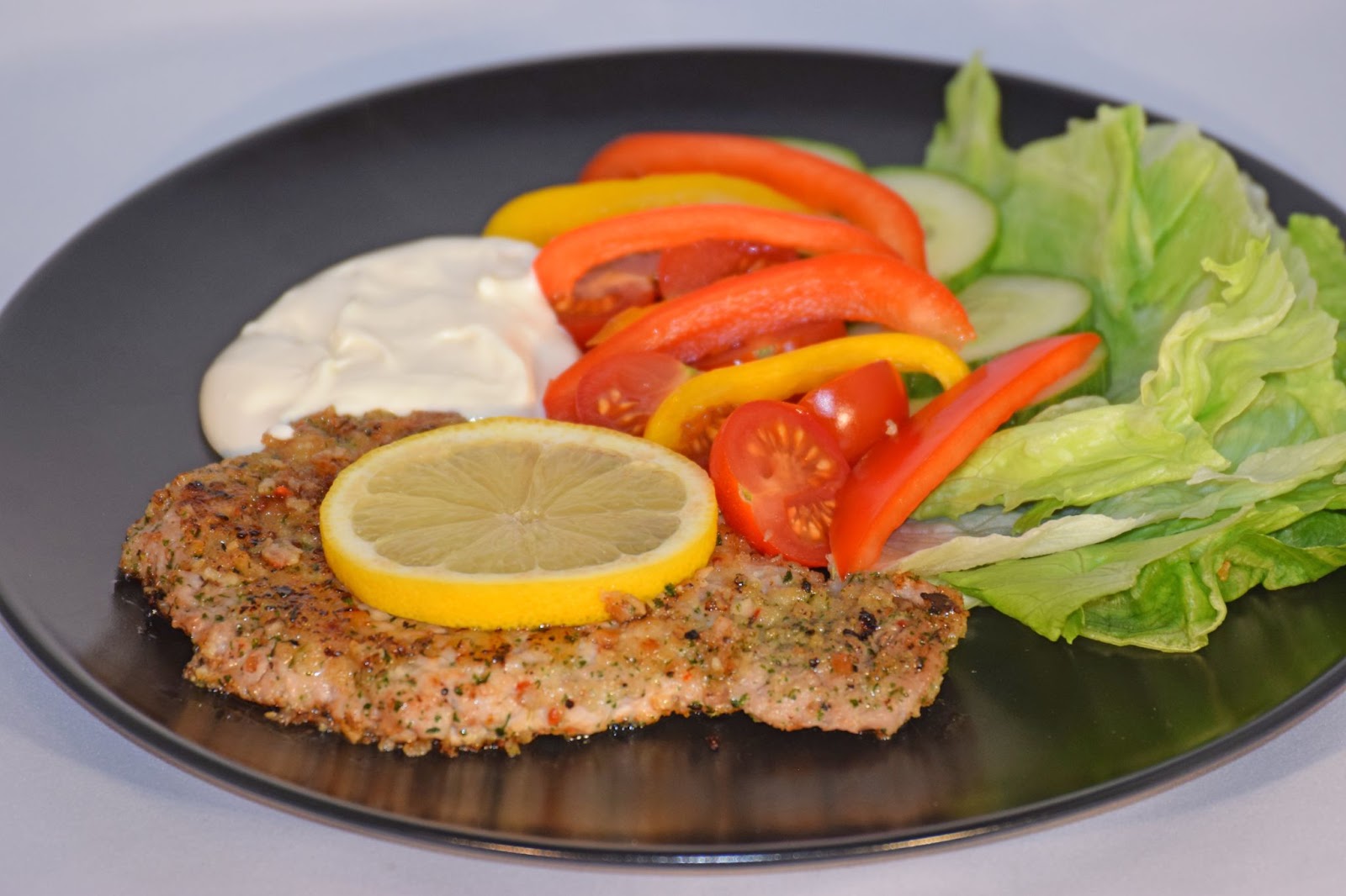 baked keto cutlets being served in a plate with salad and white sauce
