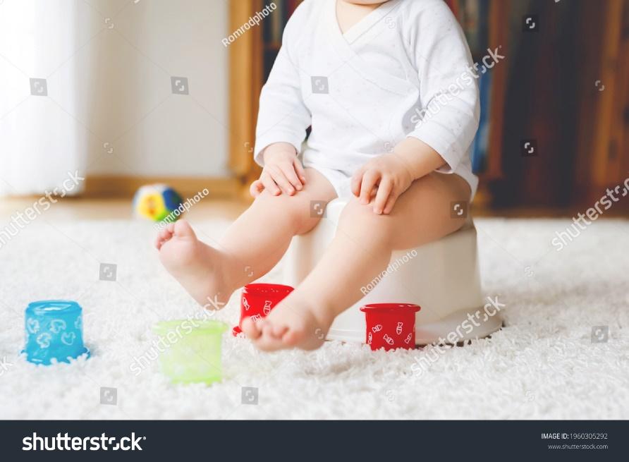 Closeup of cute little old toddler baby girl child sitting on potty. Kid playing with educational toy and Toilet training concept. Baby learning, development steps. No face, unrecognizable person.