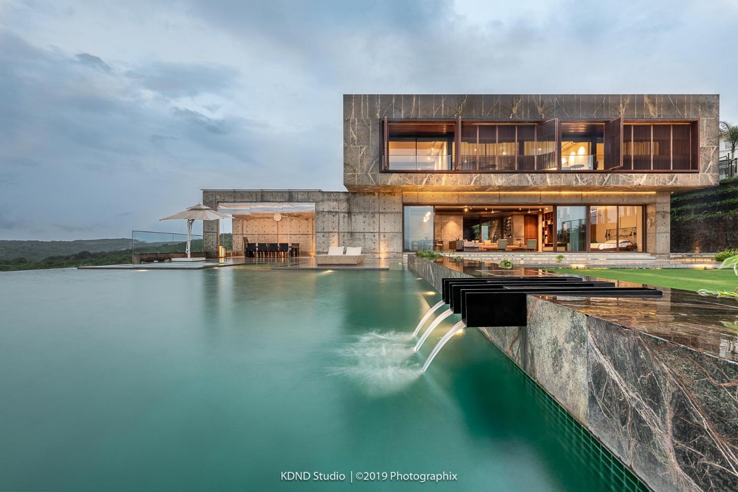 Architectural photography of a luxury house with large glass windows, overlooking an infinity pool that blends into a scenic landscape.