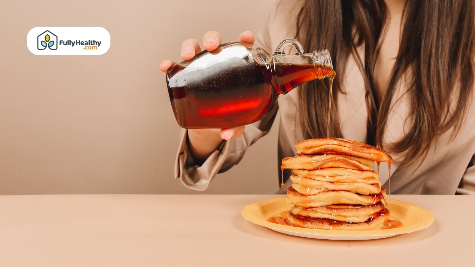 Woman pouring maple syrup over stacked fluffy pancakes