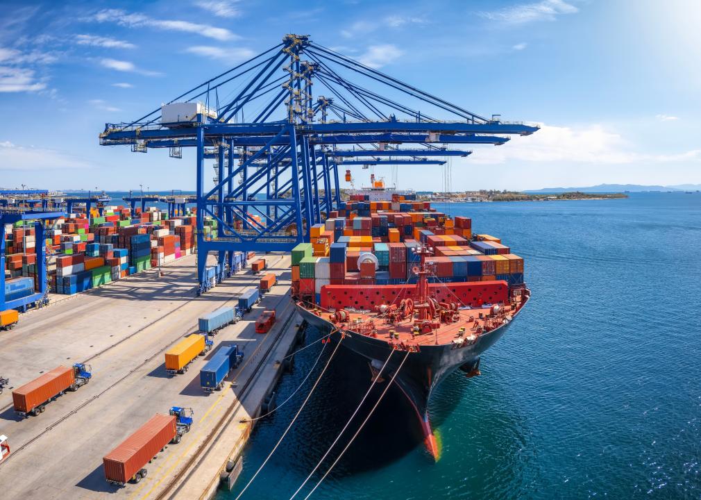 A large container cargo ship is being unloaded in a commercial dock.