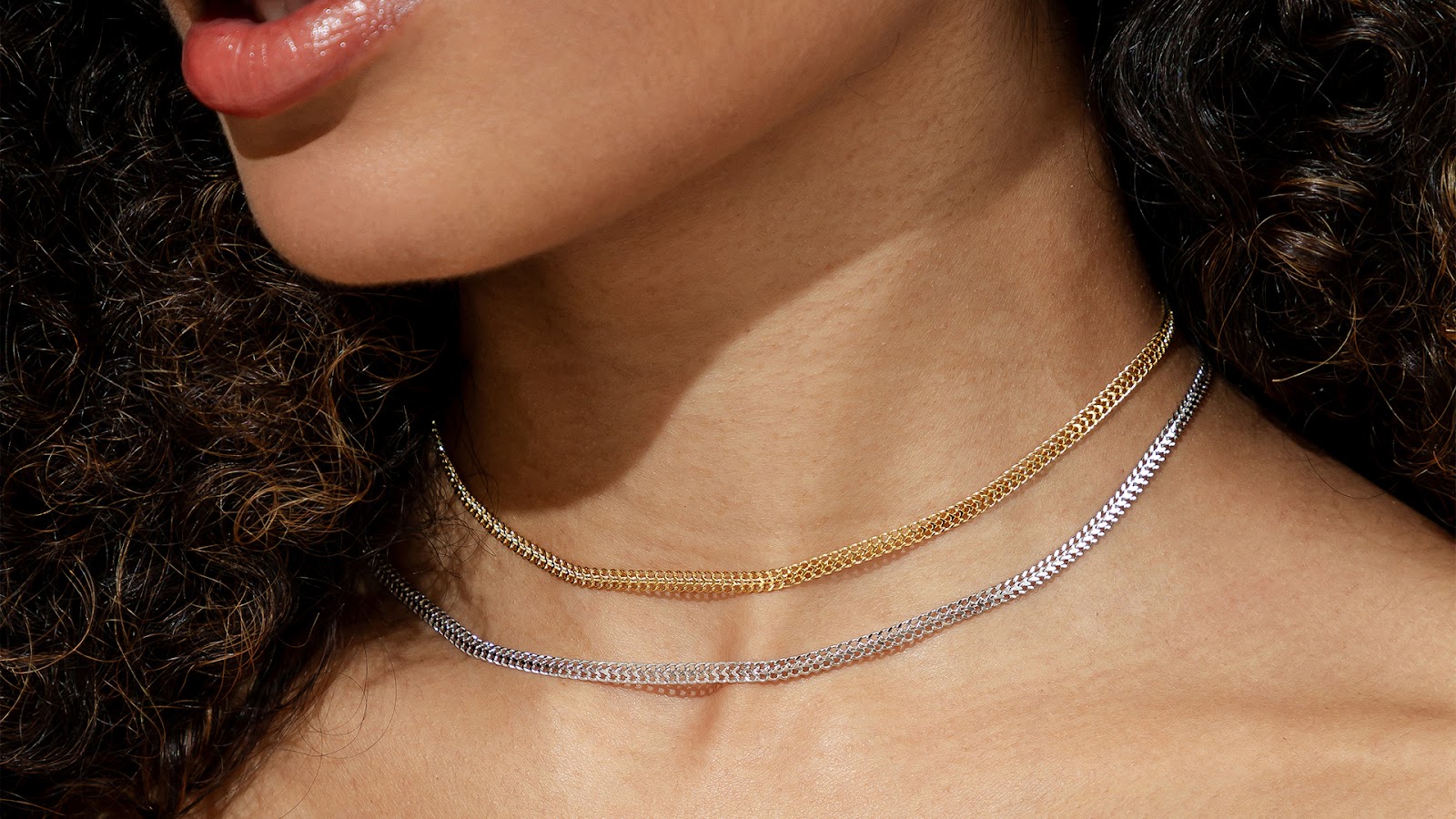 Modelo usando um mix com o mesmo modelo de colar choker, um deles no banho de ouro 18k e outro no banho de ródio branco