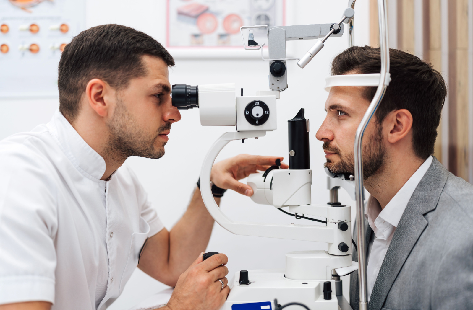 A side view of a young adult smiling during a slit-lamp eye exam to look for potential eye diseases.
