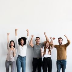 This may contain  people standing in front of a white wall with their arms up