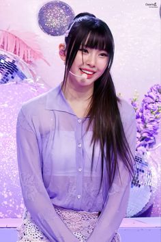 This contains an image of  NewJeans' Hyein with long black hair wearing a purple shirt