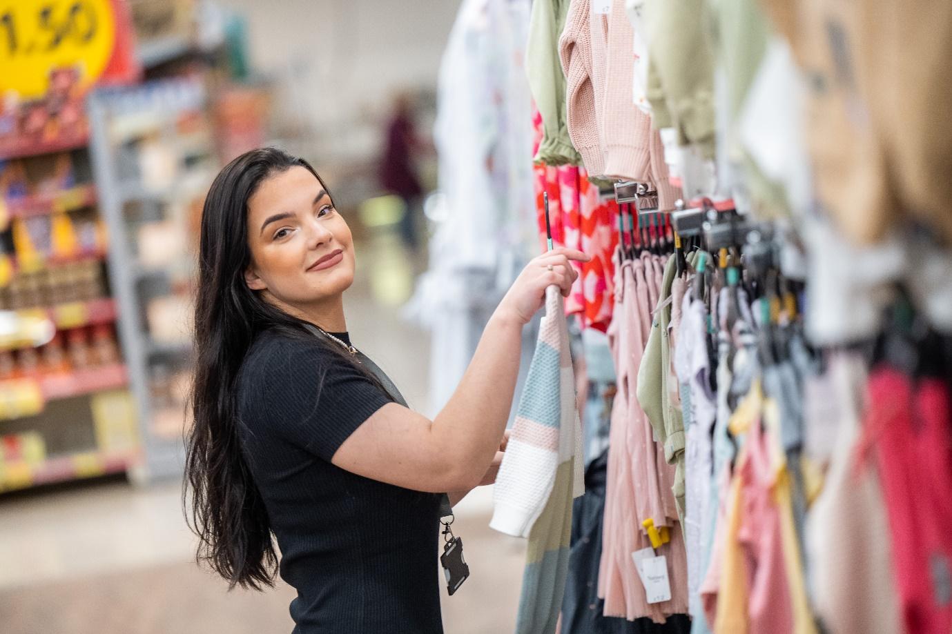 A person looking at clothes on a rack

Description automatically generated