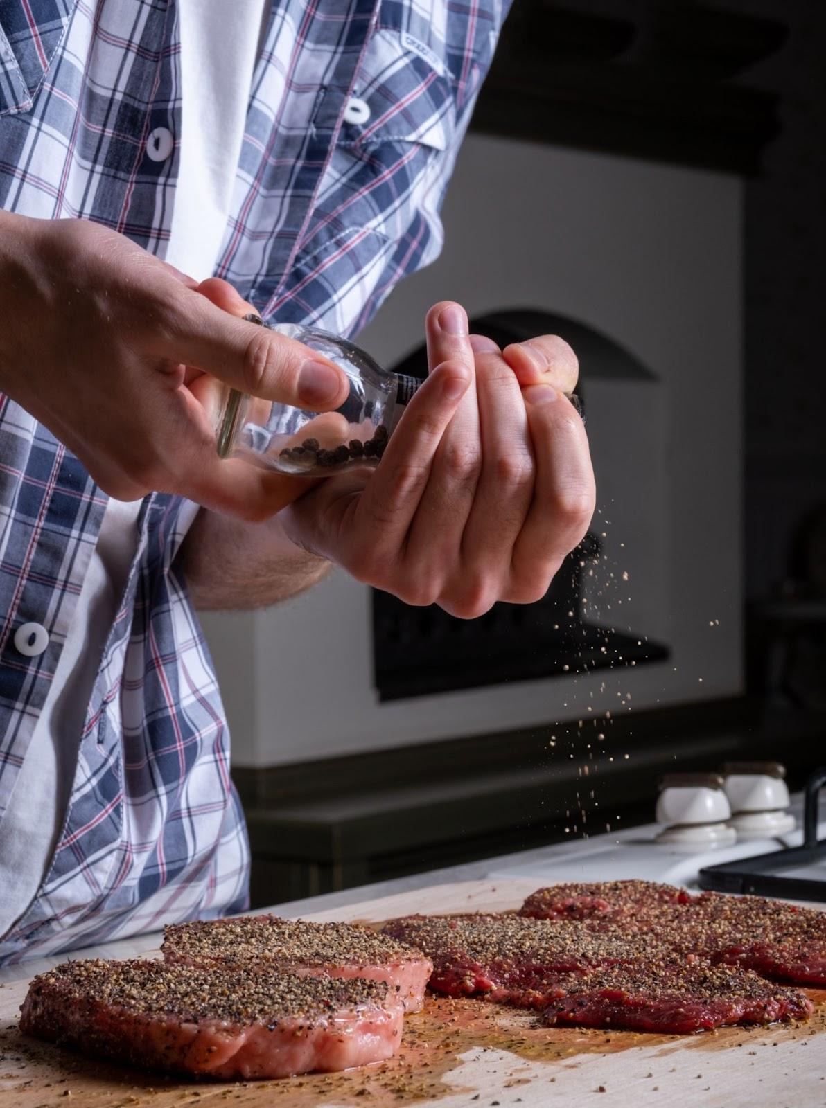 a man adding black pepper and salt into cutlets