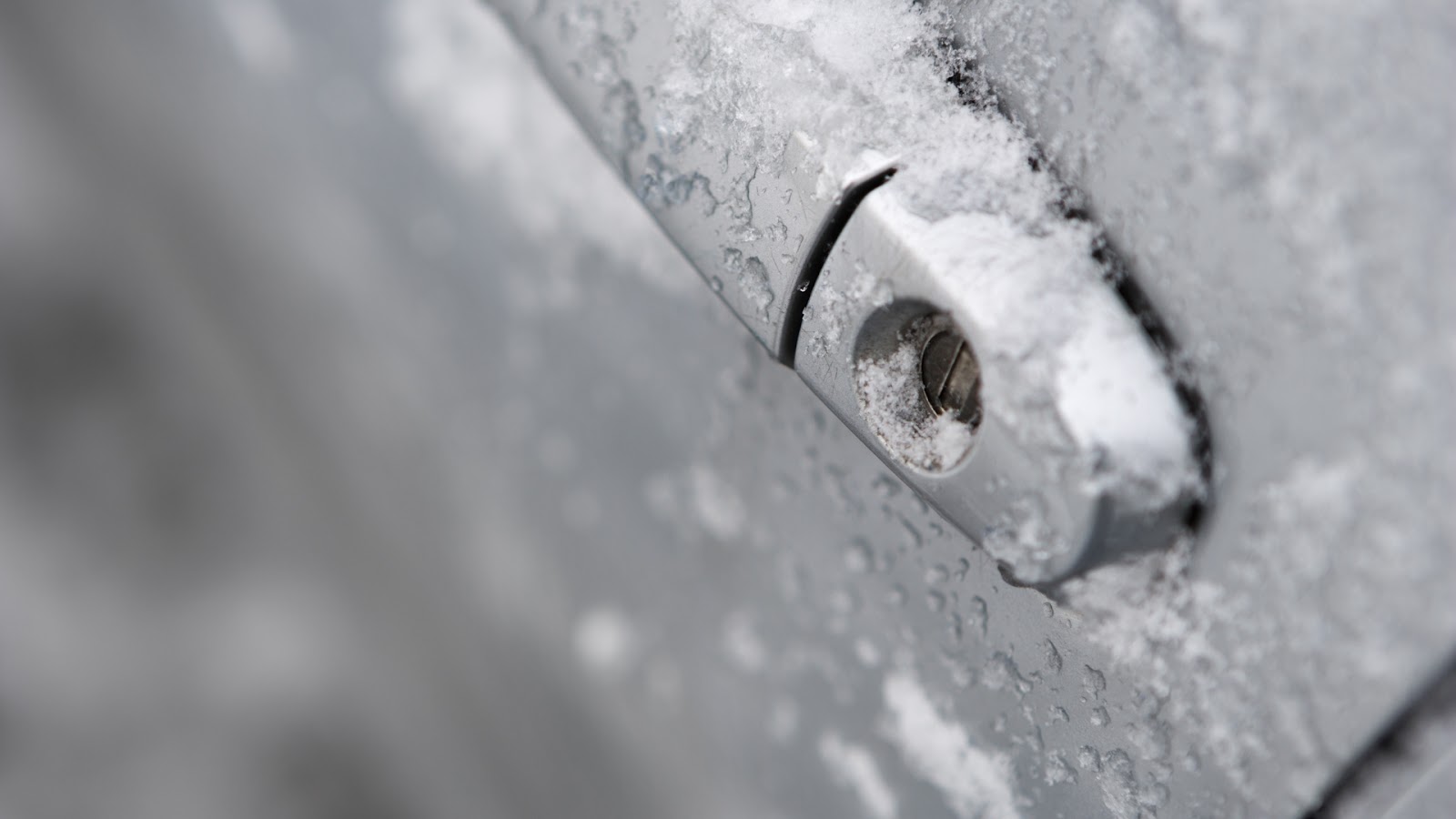 Close-up view of a car lock under frost, suggesting signs of a broken car door lock