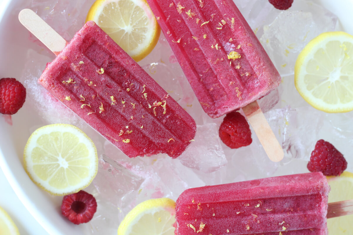 Raspberry lemonade electrolyte popsicles sitting in bowl of ice