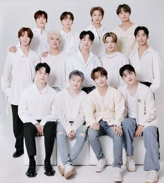 This contains an image of SEVENTEEN group members sitting next to each other in front of a white wall