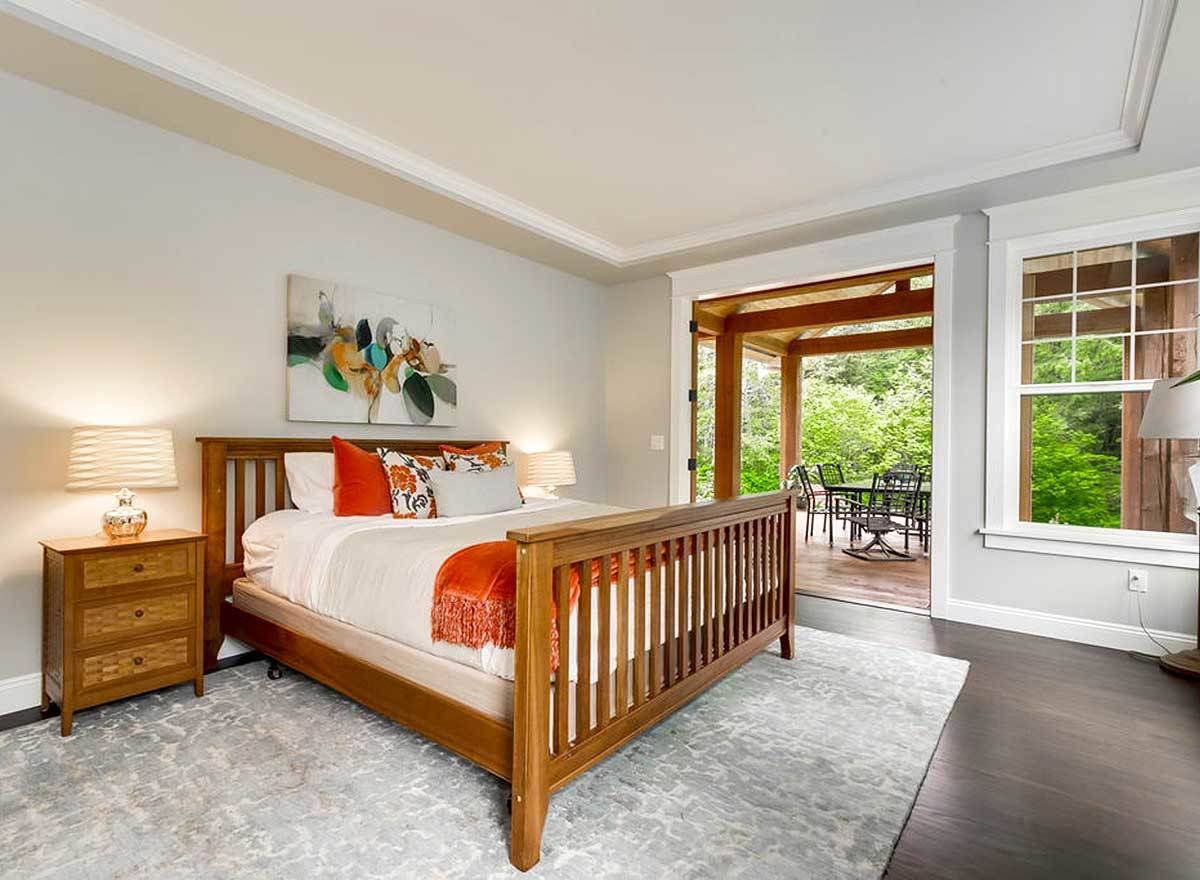 Primary bedroom with a tray ceiling, a wooden bed, and private deck access.