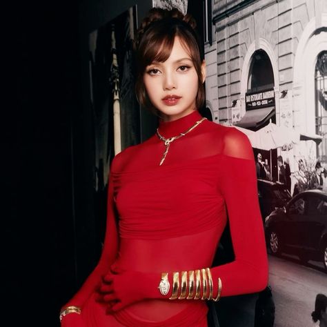 This contain BLACKPINK's Lisa in a red dress standing next to a wall