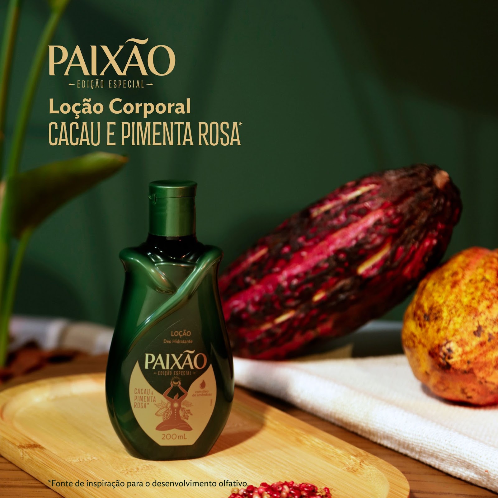 A Loção Hidratante Corporal Paixão Feminino Ancestral aparece em cima de uma bandeja de madeira em um cenário decorado com pimenta rosa e cacau.