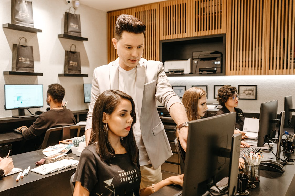 Manager supporting an employee at their computer during their first weeks, highlighting early onboarding and team development.