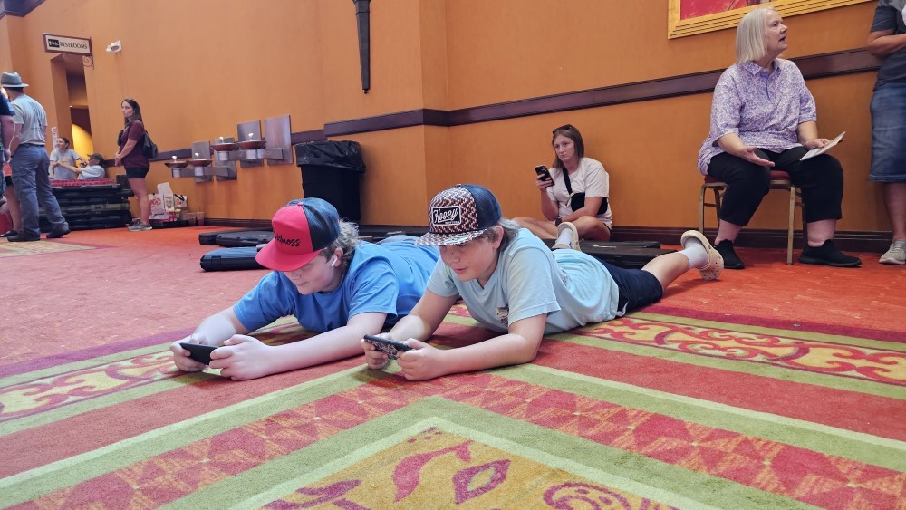 two boys laying on the floor playing videos games together. 