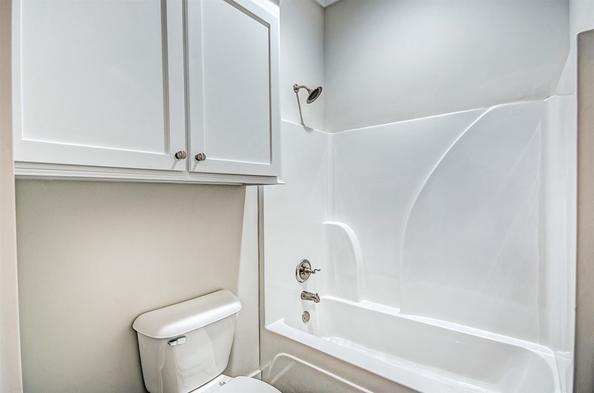 There's also a tub and shower combo and a toilet placed under a white cabinet.