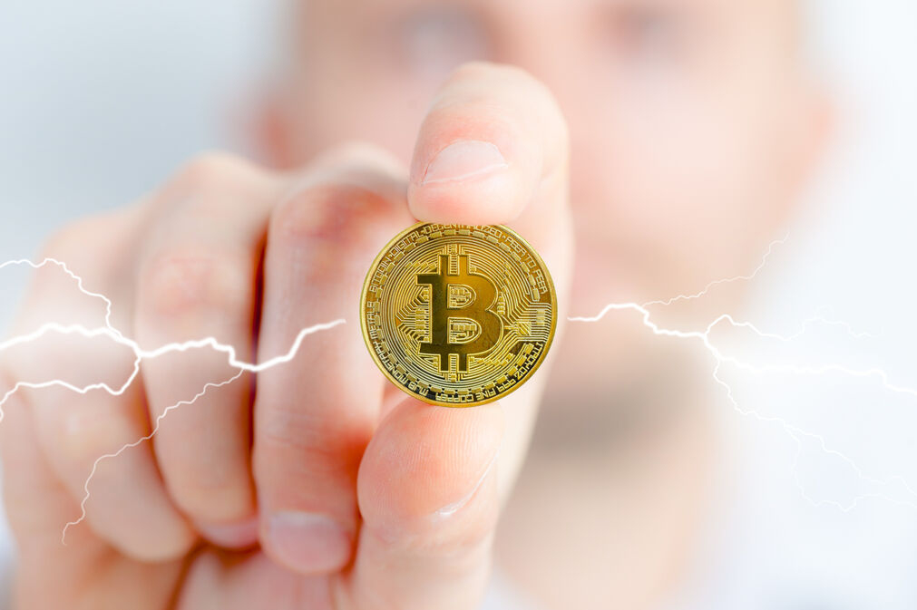 Man holding a Bitcoin coin in his hand, symbolizing cryptocurrency investment and digital currency