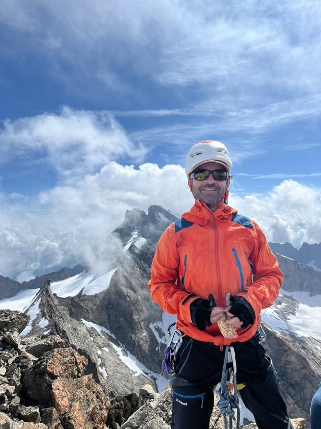 A person wearing a helmet and climbing gear standing on a mountainAI-generated content may be incorrect.