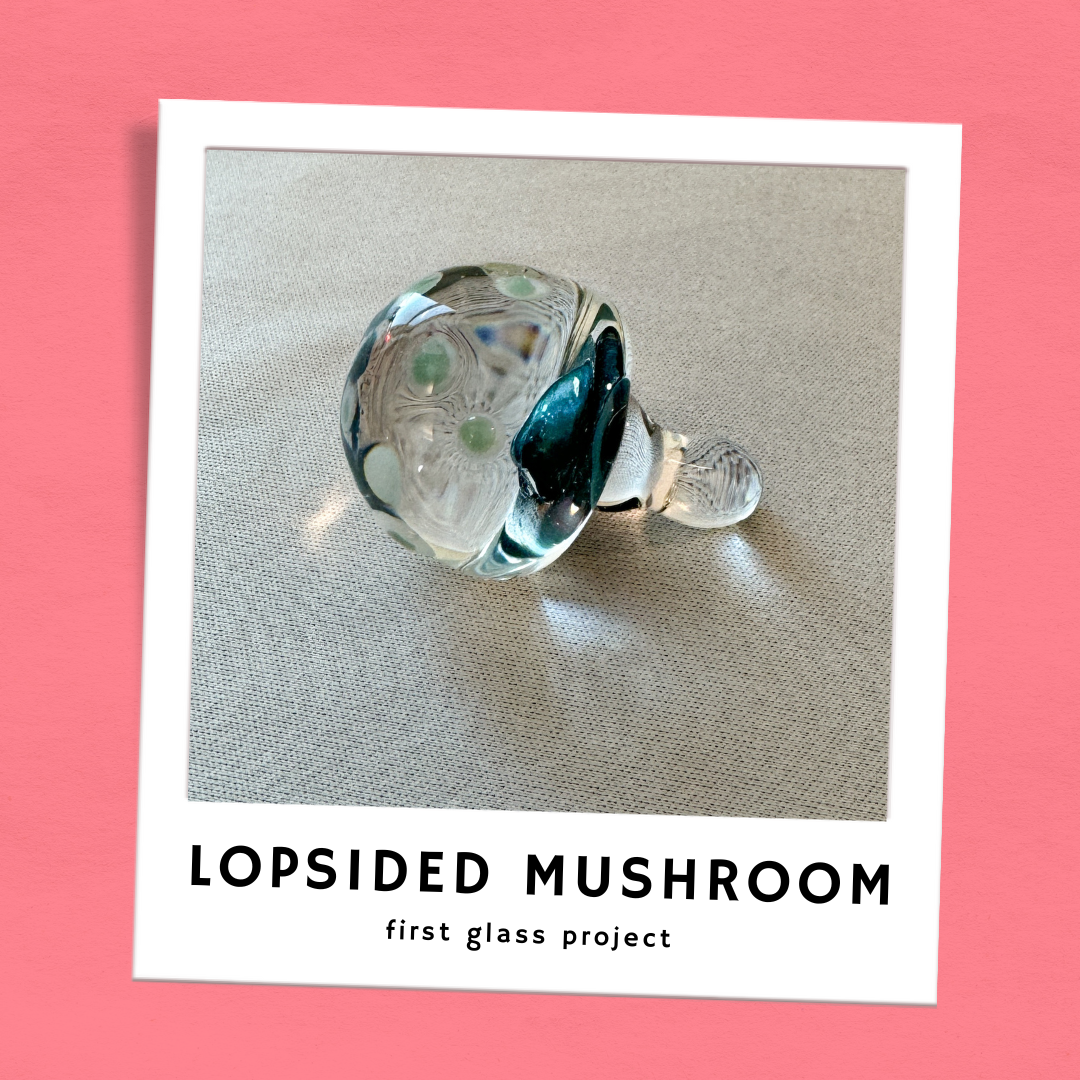 A lopsided glass mushroom lays on its side. It's labeled "First glass project."