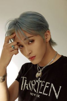 This containA picture of NCT DREAM's Mark  with blue hair wearing a black shirt and silver bracelets holding his hand to his head