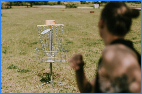 woman throwing Disc into a disc golf hole