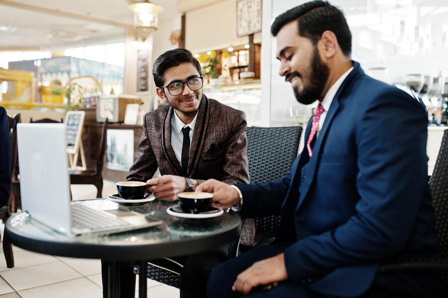 Two men sitting at a table drinking coffee.