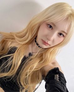 This contain Lee Chaeyeon with long blonde hair posing for the camera, wearing black clothing and bracelets