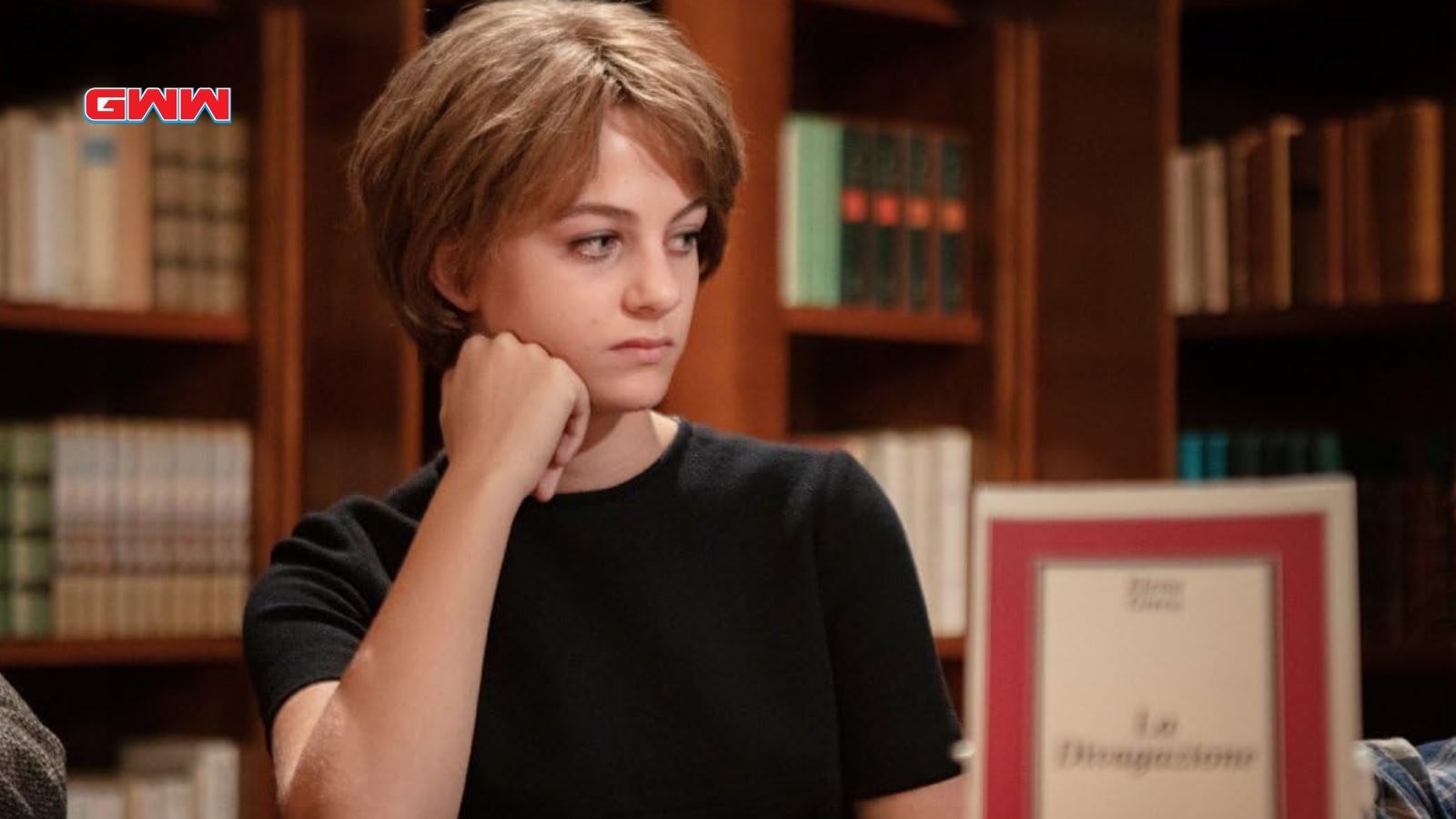 Young Elena in a library, gazing pensively to the side.